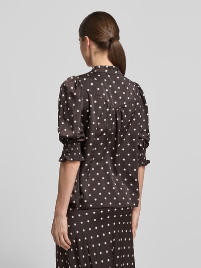 Frauenmodel trägt Regular Fit Bluse mit Stehkragen Modell 'Diana' von Neo Noir, obszycie falbanami, rękaw o dł. 1/2, elastyczne wykończenia, długość tyłu w rozmiarze 36: 59 cm, długość rękawów w rozmiarze 36: 41 cm, brązowa z białymi groszkami, Ganzkörperansicht Rückansicht.