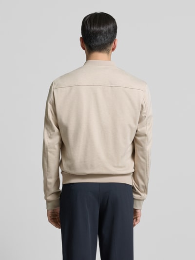 Męski model nosi Jacke mit Reißverschluss od MCNEAL w kolorze beżowym, krój regular fit, tkanina z dodatkiem stretchu, widok całej sylwetki z tyłu. Szerokość w rozmiarze M: 57 cm, długość tyłu: 63 cm, szerokość ramion: 46 cm, długość rękawa: 67 cm.