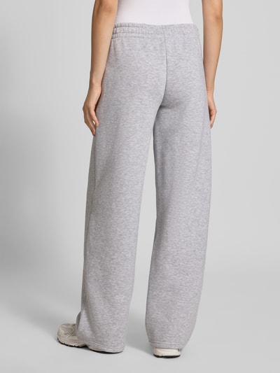 Frauenmodel trägt Sweathose in grau melange mit geradem Bein von REVIEW, Baumwoll-Mix, elastischer Bund, Logo-Print, Ganzkörperansicht Rückansicht.