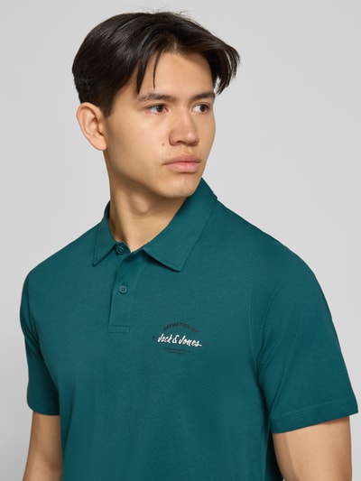 Männermodel trägt poloshirt mit labelprint model 'BRANDON' van Jack & Jones, puur katoen, regular fit, polokraag, knoopsluiting, labelprint, ruglengte bij maat M 71 cm, nahaufnahme bovenlichaam.