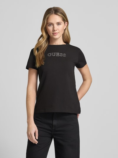 Frauenmodel trägt T-Shirt mit Logo Modell 'BRIANA' von Guess Activewear in Schwarz, Baumwoll-Elasthan-Mix, Nahaufnahme Oberkörper.