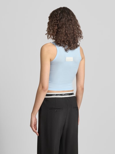 Frauenmodel trägt Slim Fit Top mit Logo-Detail von ANOTHER COTTON LAB, hellblau, elastischer Baumwoll-Mix, Rückansicht, Ganzkörperansicht.