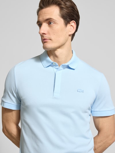 Męski model nosi Regular Fit Poloshirt aus Baumwoll-Mix von Lacoste, efekt: jednolity kolor, wyhaftowane logo, pika, mieszanka bawełny, krótki rękaw, kołnierzyk polo, prążkowane zakończenie rękawów, z bocznymi rozcięciami, zbliżenie na górną część ciała