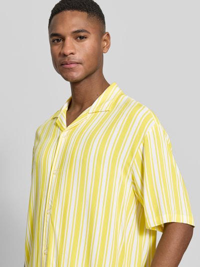 Männermodel trägt Regular Fit Freizeithemd aus reiner Viskose Modell 'Resort' von MCNEAL, gelb-weiß gestreift, Nahaufnahme Oberkörper.