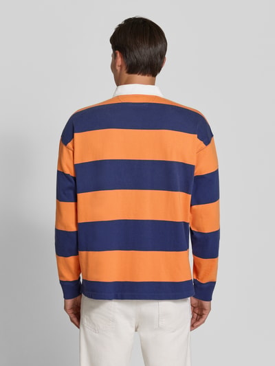 Mannenmodel draagt oversized pullover van katoen model '6/1' van Polo Ralph Lauren in oranje en donkerblauw gestreept, rechte vormen, Heren pullover van Polo Ralph Lauren, volledige lichaamsweergave achterkant.