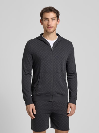 Männermodel trägt Sweatjacke mit Logo-Muster und Kapuze von JOOP! Collection, Reine Baumwolle, Regular-Fit, Eingrifftaschen, Reißverschluss, Farbe Dunkelgrau, Strukturmuster, Rückenlänge 69 cm, Ärmellänge 63 cm, Ganzkörperansicht von vorne.