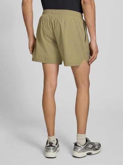 Männermodel trägt Shorts mit elastischem Bund und Label-Print von HALO in Beige, Material-Mix mit Stretch, Ganzkörperansicht Rückansicht.