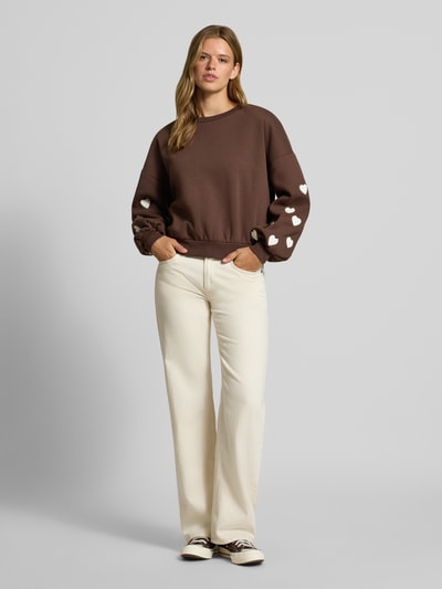 Vrouwenmodel draagt Regular fit sweatshirt uit katoenmix model 'MACY' van ONLY, bruin met witte hartjes, Dames sweatshirt, geheel vooraanzicht.