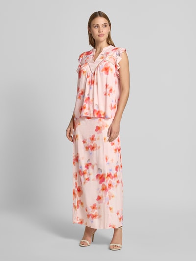 Frauenmodel trägt Blusentop aus Viskose mit V-Ausschnitt Modell 'Mirava' von mbyM, Regular-Fit, Rüschen, Rückenlänge 61 cm, Ärmellänge 8 cm, zartes florales Muster in Rosa und Orange, weiche fließende Textur, Ganzkörperansicht von vorne.