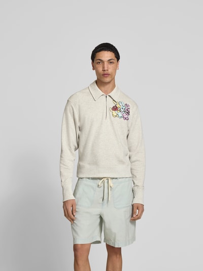 Männermodel trägt Pullover mit Pailettenbesatz von Kenzo aus reiner Baumwolle, Strick-Optik, Regular Fit, helle Farben, Ganzkörperansicht von vorne.