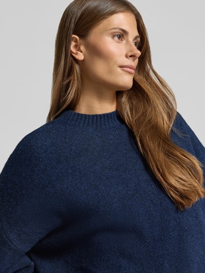 Vrouwenmodel draagt oversized pullover met wol model 'BOOM' van VERO MODA in donkerblauw, structuur fijn, Nahaufnahme bovenlichaam.