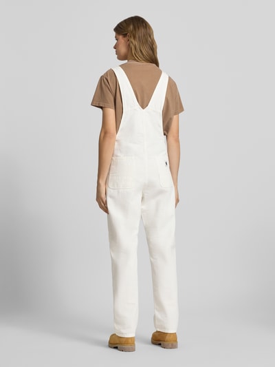 Frauenmodel trägt Overall mit Brusttasche Modell 'BIB' von Carhartt Work In Progress aus Reine Baumwolle in Straight Fit, Eingrifftaschen, Gesäßtaschen, Label-Patch, weiß, Ganzkörperansicht Rückansicht.