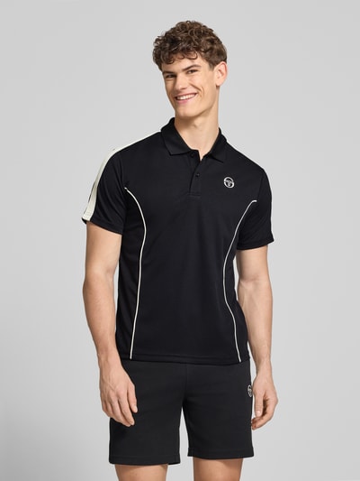 Męski model nosi Regular Fit Poloshirt mit Logo-Stitching Modell 'EGEO' von SERGIO TACCHINI w kolorze czarnym z białymi akcentami, krótki rękaw, kołnierzyk polo, widok całej sylwetki z przodu, długość tyłu w rozmiarze M: 66 cm.