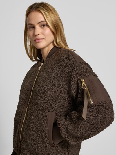 Frauenmodel trägt Teddyjacke mit Stehkragen Modell 'Emeline' von MOS MOSH in Braun, goldfarbener Reißverschluss, strukturierte Oberfläche, Nahaufnahme Oberkörper. Lockere Passform, Reißverschlusstasche am Ärmel, seitliche Eingrifftaschen, elastische Abschlüsse.