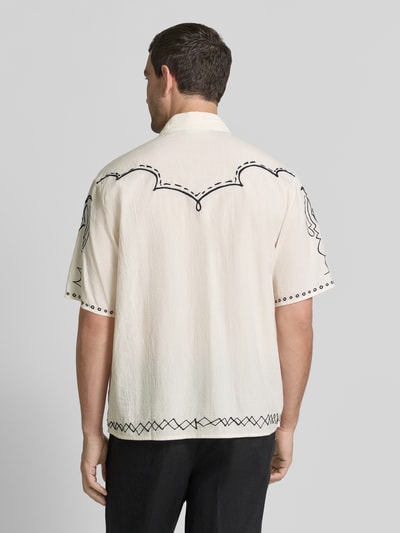 Mannelijk model draagt Regular Fit vrijetijdsoverhemd met kentkraag en stitchings van Scotch & Soda, puur katoen, ruglengte maat M 73 cm, schouderbreedte maat M 49 cm, mouwlengte maat M 28 cm, crèmekleur met zwarte details, textuur licht geribbeld, geheel aanzicht rugzijde.