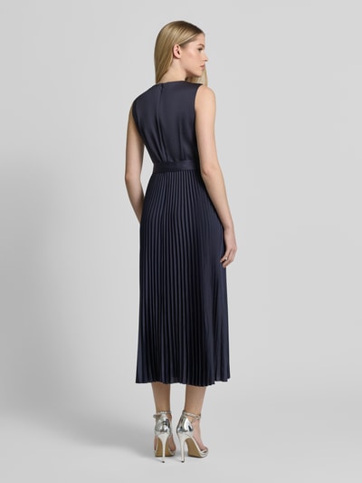 Modelka nosi 'Cocktailkleid mit Plisseefalten' od Vera Mont w kolorze ciemnogranatowym, długość midi, taliowany krój, okrągły dekolt, pasek, plisowane fałdy, zamek z tyłu, długość tyłu w rozmiarze 36: 126 cm, szerokość w rozmiarze 36: 30 cm, widok tyłu całej sylwetki.