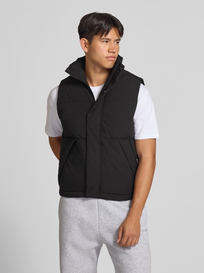 Männermodel trägt zwarte bodywarmer van JACK & JONES Model 'SOHO BODYWARMER', regular fit, opstaande kraag, verborgen ritssluiting, ruglengte maat M 65 cm, schouderbreedte maat M 43 cm, borstwijdte maat M 59 cm, productfoto, Ganzkörperansicht von vorne.