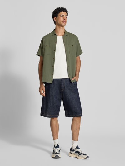 Männermodel trägt Regular Fit Freizeithemd mit Kentkragen und Brusttaschen von Superdry in Grün, Strukturmuster, Ganzkörperansicht von vorne.