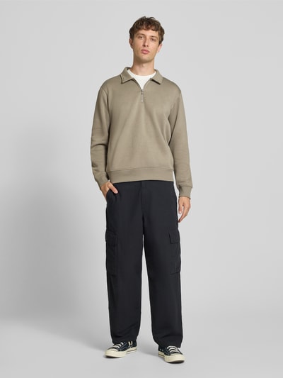Männermodel trägt Regular Fit Sweatshirt mit Baumwoll-Anteil Modell 'Bradley' von JACK & JONES in Beige, Material-Mix, Troyer-Kragen, Reißverschluss, Ganzkörperansicht von vorne.