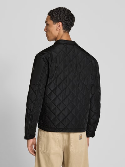 Männermodel trägt Regular Fit Jacke in Stepp-Optik von Replay, schwarze Farbe, Rautenstruktur, Rückansicht, Ganzkörperansicht Rückansicht. Herren Jacke mit Stehkragen, Druckknopfverschluss, Reißverschlusstaschen, Logo-Print, Maße: Rückenlänge 65 cm, Schulterbreite 29 cm, Brustweite 38 cm, Ärmellänge 63 cm.