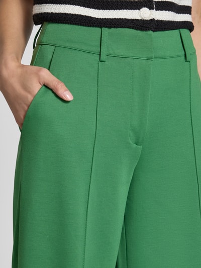 Frauenmodel trägt Wide Fit Hose mit Viskose-Anteil Modell 'Kate' von ICHI in Grün mit Ziernähten und Gesäßtaschen, Nahaufnahme Oberkörper.