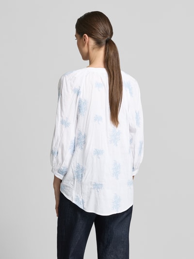 Frauenmodel trägt Bluse aus Viskose-Mix mit verlängertem Rücken von Apricot, weiß mit blauem Muster, Loose-Fit, Rückenlänge 68 cm, Ganzkörperansicht Rückansicht.