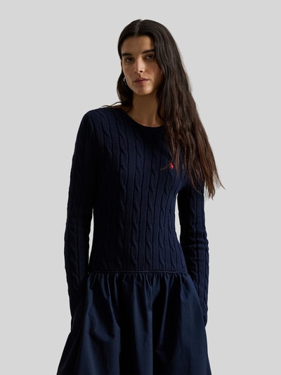 Vrouwenmodel draagt 'Ausgestelltes Strickkleid aus Woll-Mix mit Kaschmir-Anteil' van Polo Ralph Lauren in uni donkerblauw, kabelpatroon, maxi, ronde hals, logo-stiksel, lange mouwen met geribde boorden, zij-insteekzakken, gebreide materiaalmix, detailopname bovenlichaam.
