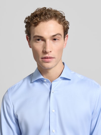 Männermodel trägt Slim Fit Businesshemd aus Twill von ETERNA in Hellblau, Haifischkragen, Knopfleiste, feine Webstruktur, Nahaufnahme Oberkörper.