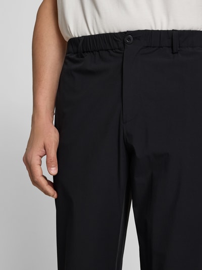Männermodel trägt Stoffhose mit Stretch-Anteil von Forét, Schwarz, Elastischer-Material-Mix, Relaxed-Fit, Nahaufnahme Oberkörper.