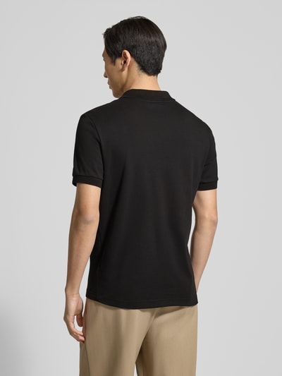 Männermodel trägt Regular Fit Poloshirt aus reiner Baumwolle von Lacoste, Optik: Unifarben, Kurzarm, Ganzkörperansicht Rückansicht.