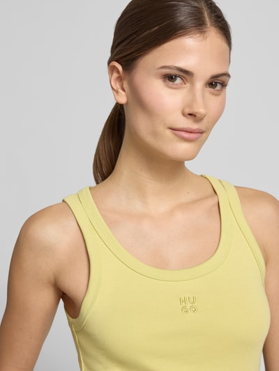 Frauenmodel trägt Slim Fit Tank Top aus Baumwoll-Mix Modell 'DATAMIA' von HUGO in Unifarbe Gelb, U-Ausschnitt, Feinripp, Nahaufnahme Oberkörper.