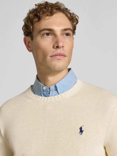 Männermodel trägt Relaxed Fit Pullover aus reiner Baumwolle von Polo Ralph Lauren in Creme mit glatter Textur, Nahaufnahme Oberkörper. Herren Pullover von Polo Ralph Lauren