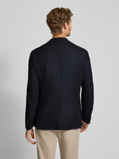 Männermodel trägt dunkelblaues Slim Fit Sakko mit Schurwoll-Anteil Modell 'P-Hanry-WG-264' von BOSS, strukturierte Webware, Ganzkörperansicht Rückansicht.