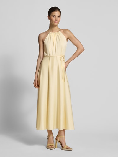Vrouwenmodel draagt Cocktailkleid aus Satin mit Bindegürtel van Jake*s Cocktail in lichtgeel satijn, a-lijn, halternek, riem, volledige vooraanzicht.