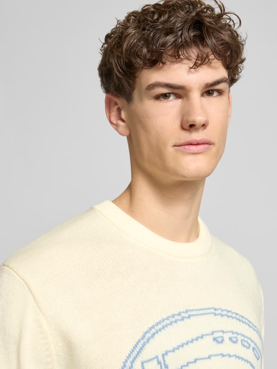 Männermodel trägt Strickpullover mit Logo und Rundhalsausschnitt von Dickies, cremefarben, Regular Fit, Nahaufnahme Oberkörper.