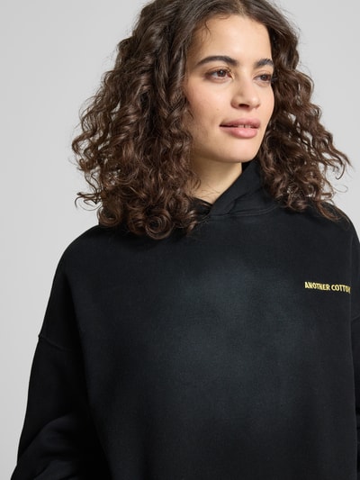 Modelka nosi Hoodie mit Logo-Stitching von ANOTHER COTTON LAB, mieszanka bawełny, luźny krój, kaptur, wyhaftowane logo, kieszeń kangurka, Nahaufnahme górnej części ciała.