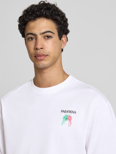 Męski model nosi Boxy Fit T-Shirt aus reiner Baumwolle Modell 'FRED ESCAPE' od Only & Sons, biały, motywowy nadruk, jersey, unikolor, krótki rękaw, dekolt okrągły, Nahaufnahme górnej części ciała.