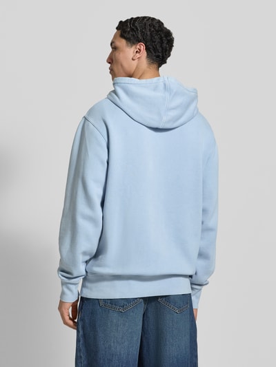 Männermodel trägt Hoodie mit Label-Stitching und Känguru-Tasche von Dickies, hellblau, Baumwoll-Mix, Relaxed Fit, Ganzkörperansicht Rückansicht.