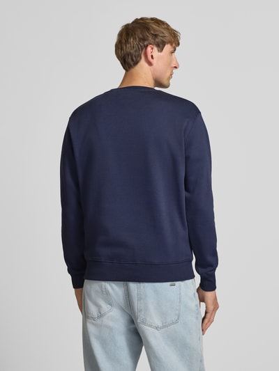 Männermodel trägt Regular Fit Sweatshirt aus Baumwoll-Mix mit Label-Detail von Alpha Industries in Dunkelblau, Rückenansicht, Herren Sweatshirt, elastische Abschlüsse, 67 cm Rückenlänge, 63 cm Ärmellänge.