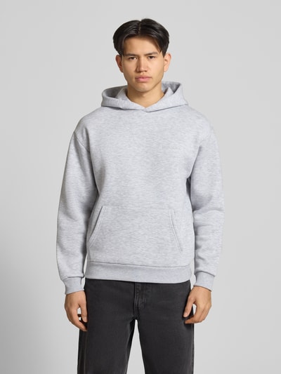 Männermodel trägt Hoodie mit Känguru-Tasche von REVIEW in Grau, Baumwollmischung, lockere Passform, Label-Detail, Ganzkörperansicht von vorne.