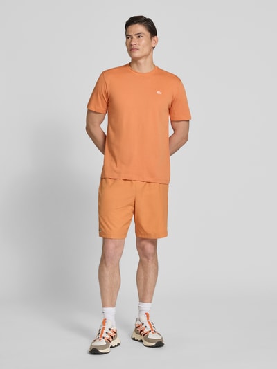 Männermodel trägt Regular Fit T-Shirt aus Baumwoll-Mix von Lacoste in Optik: Unifarben, Logo-Applikation, schnelltrocknend, Ganzkörperansicht von vorne.