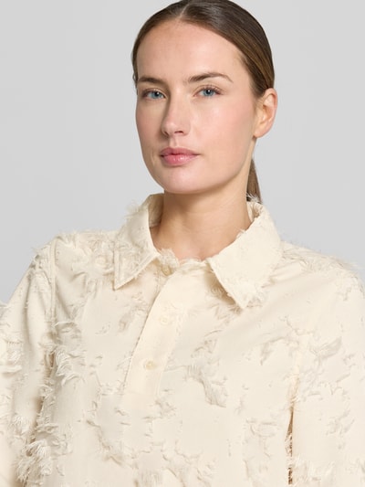 Frauenmodel trägt Minikleid mit kurzer Knopfleiste Modell 'Mialle' von mbyM in Creme mit Strukturmuster, Polokragen, Nahaufnahme Oberkörper. Rückenlänge 89 cm, Brustweite 34 cm, Ärmellänge 36 cm bei Größe S.