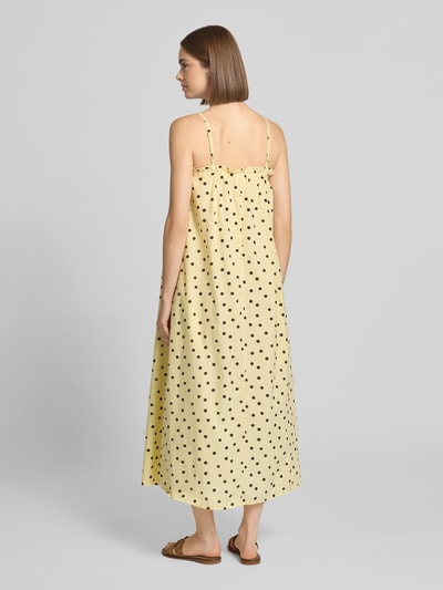 Modelka kobieca ma na sobie Loose Fit Freizeitkleid aus reiner Baumwolle Modell 'PARKER' od PIECES, jasny żółty z czarnymi kropkami, sukienki casualowe, tekstura gładka, widok całej sylwetki z tyłu.