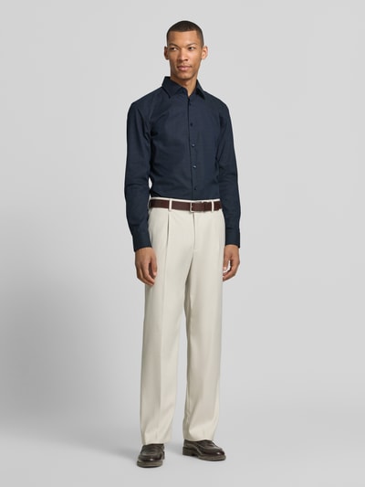 Męski model nosi Slim Fit Businesshemd aus Baumwoll-Mix Modell 'HANK' von BOSS, kolor granatowy, kołnierzyk typu kent, popelina, krój slim fit, długa listwa guzikowa, długi rękaw, mankiet, pas na plecach, mieszanka bawełny; ganzkörperansicht von vorne.