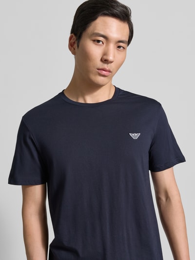 Männermodel trägt T-Shirt mit Logo-Patch und Rundhalsausschnitt von Emporio Armani in Dunkelblau, reine Baumwolle, Nahaufnahme Oberkörper