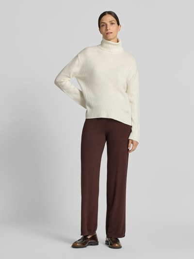 Frauenmodel trägt Oversized Pullover aus Viskose-Mix Modell 'SILJE' von VERO MODA in Creme zu brauner Hose, glatte Textur, Ganzkörperansicht von vorne. Damen Pullover von VERO MODA.