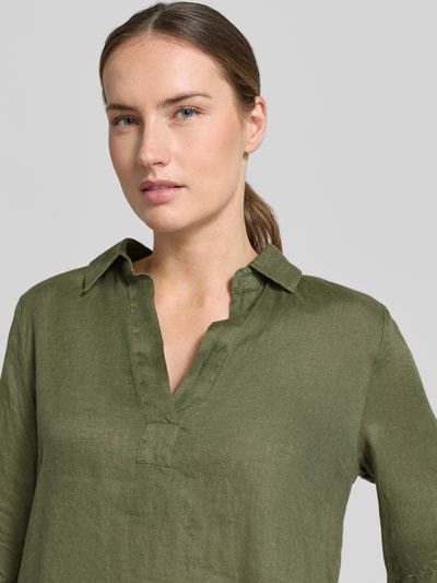 Frauenmodel trägt knielanges Leinenkleid Modell 'DERRY' von 0039 Italy in Olivgrün, mit Hemdblusenkragen und V-Ausschnitt, Nahaufnahme Oberkörper. Reines Leinen, Gerader-Schnitt, Kontext: Rückenlänge 99 cm, Brustweite 53 cm, Ärmellänge 37 cm.