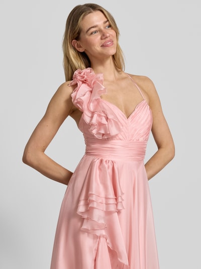 Kobiece modelka nosi 'Abendkleid mit Volants und Herz-Ausschnitt' od V.M., satyna, kolor jasnoróżowy, linia A, maksisuknia, sercowy dekolt, tylne skrzyżowane cienkie ramiączka, falbany, zapięcie na zamek i haftkę z tyłu, długość tyłu w rozmiarze 36: 122 cm, szerokość w rozmiarze 36: 32 cm, widok na górną część ciała z przodu.
