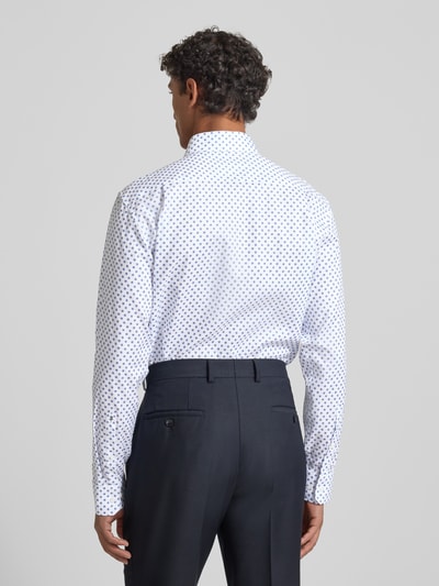 Męski model nosi Regular Fit Business Koszulę z bawełny z kołnierzykiem typu kent od SEIDENSTICKER, biała w granatowe kropki, długość tyłu 81 cm, szerokość ramion 47 cm, długość rękawów 66 cm, listwa guzikowa, widok całej sylwetki z tyłu.
