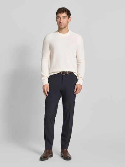 Męski model nosi Strickpullover mit gerippten Abschlüssen od MAERZ Muenchen, czysta wełna, krój regular fit, kremowy kolor, widok całej sylwetki z przodu. Długość tyłu w rozmiarze 50: 66 cm, długość rękawa w rozmiarze 50: 76 cm, okrągły dekolt, prążkowane wykończenia.